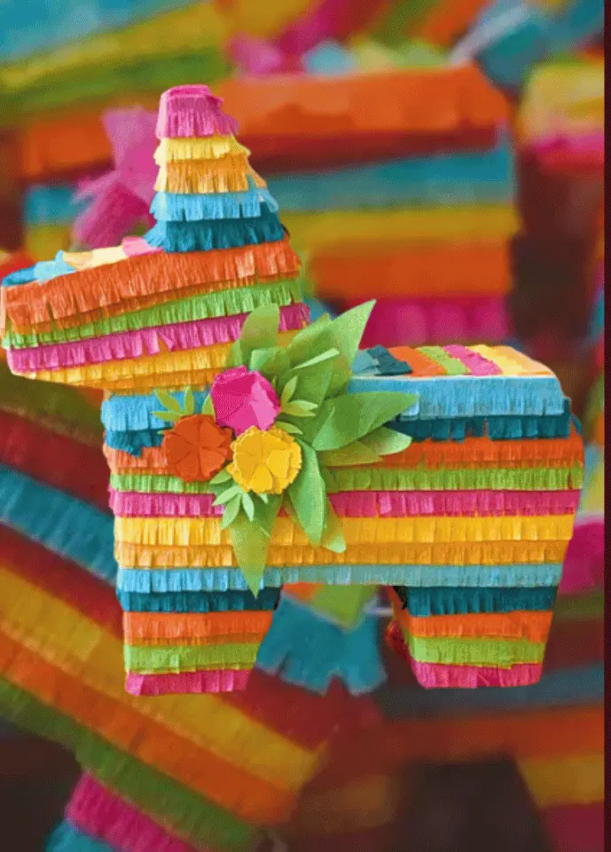 Vibrant piñata party setup with papel picado, festive decorations and margaritas