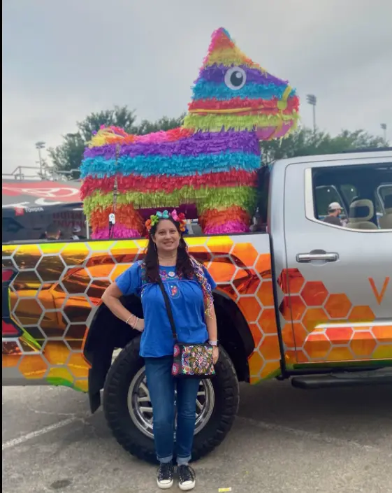 Real adult piñata party — woman standing in front of giant rainbow piñata on truck