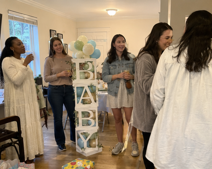 Real blocks baby shower — guests mingling next to BABY block tower with teal and green balloon garland