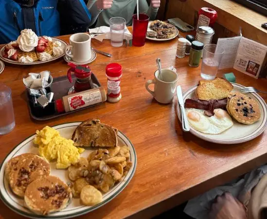 Full table spread of breakfast foods — pancakes, eggs, waffles and bacon