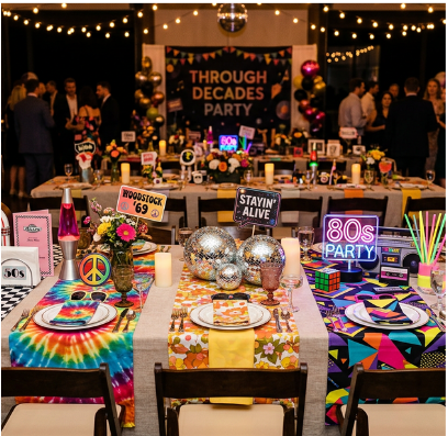 Through the decades table setup with decade signs, disco balls, and neon decor