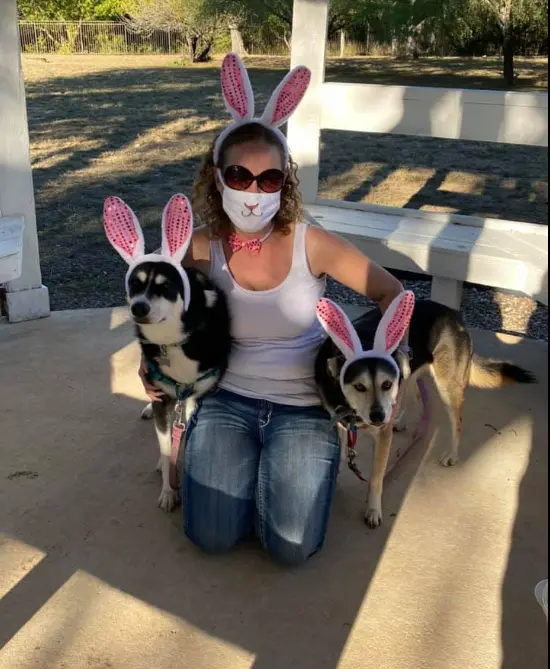 Real doggy Easter egg hunt — woman and two dogs with matching bunny ear headbands