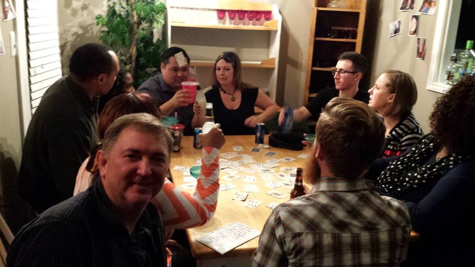 Real game night party — large group playing cards and board games together