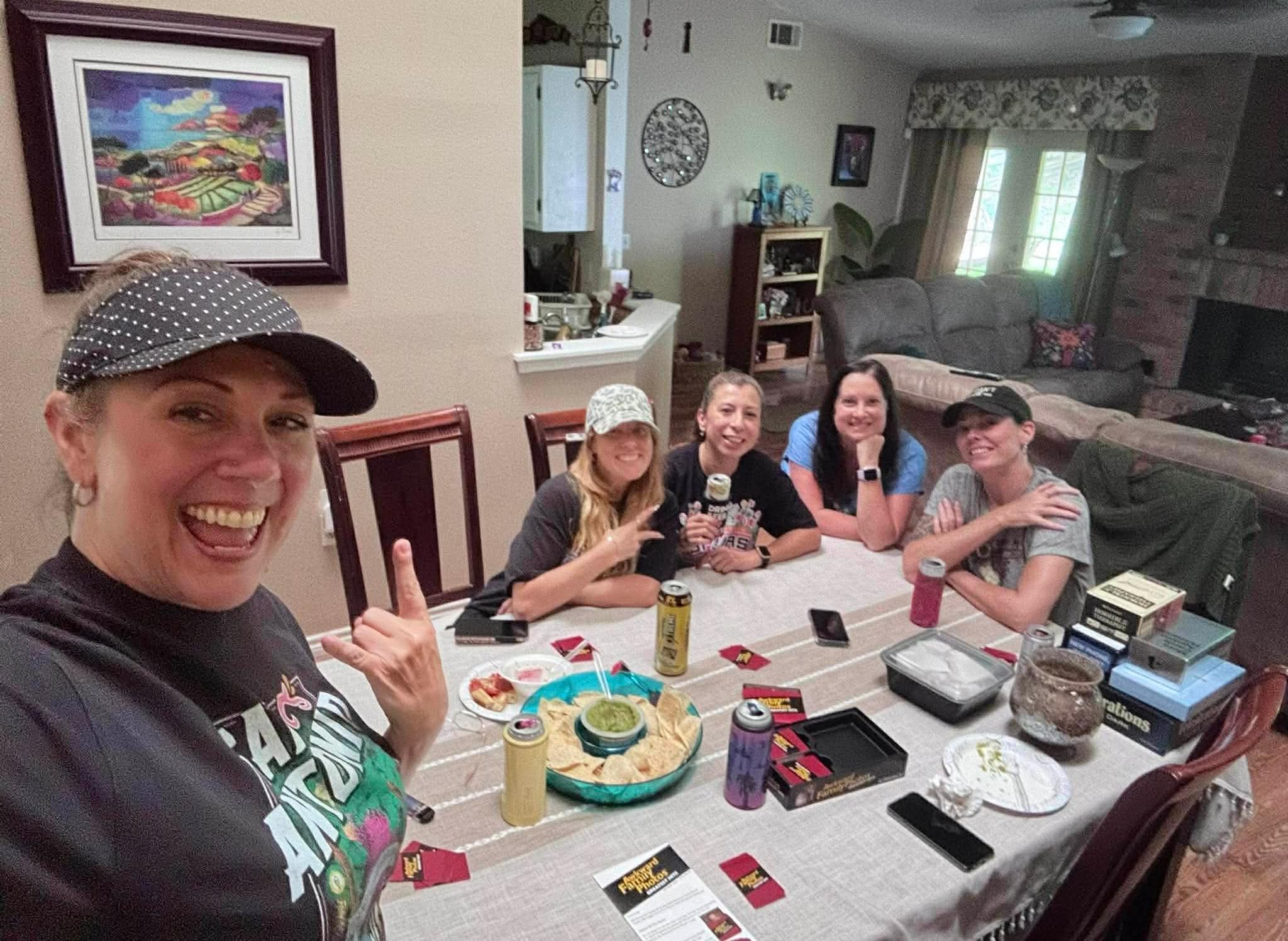 Real game night party — women at table with Cards Against Humanity and snacks