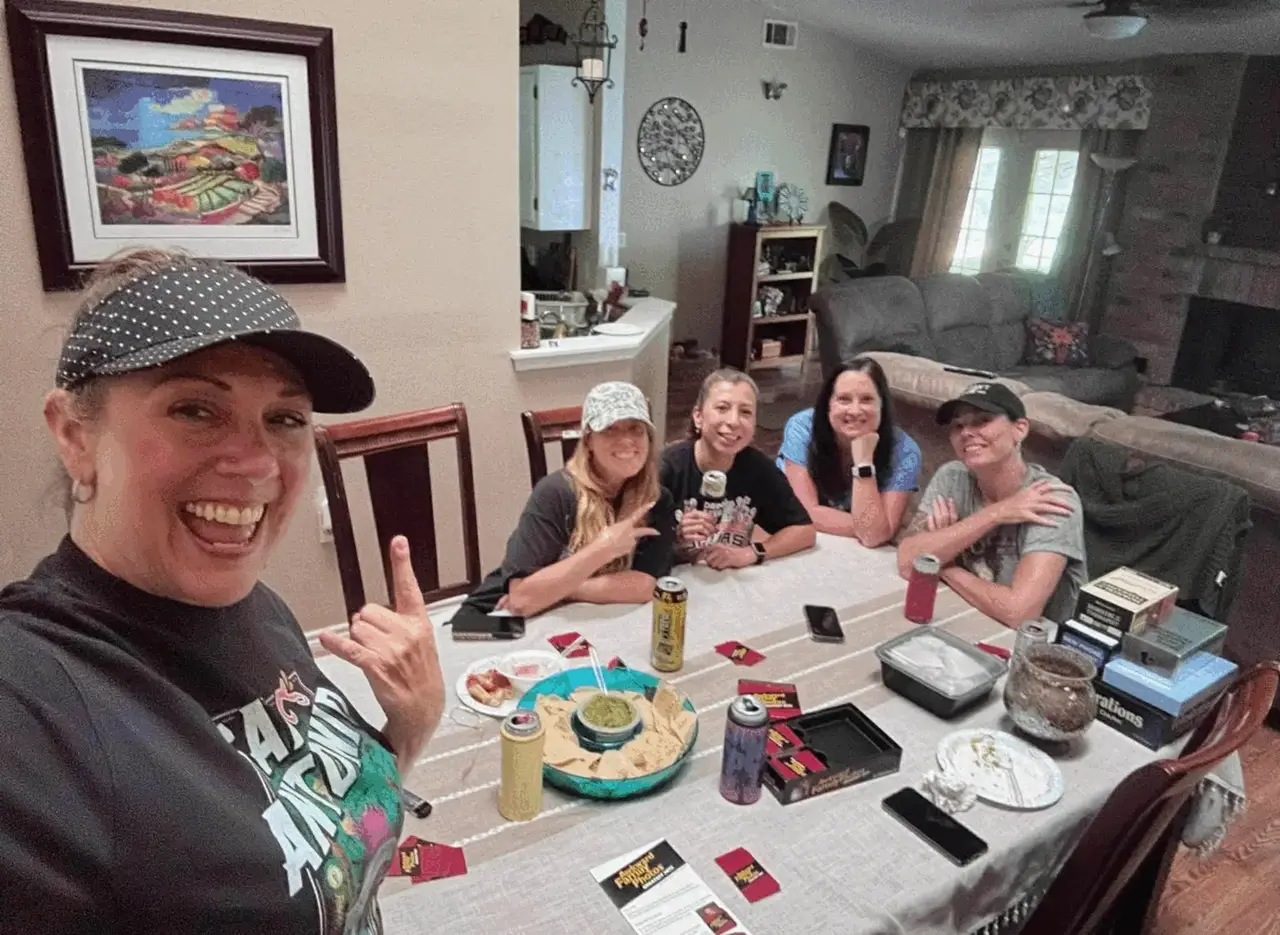 Real game night party — women at table with Cards Against Humanity and snacks