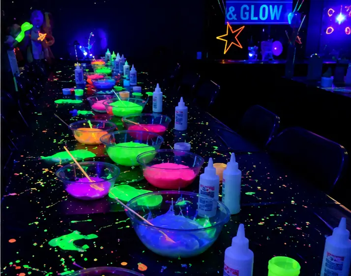Glow party inspiration — neon paint party table setup with glowing bowls and brushes