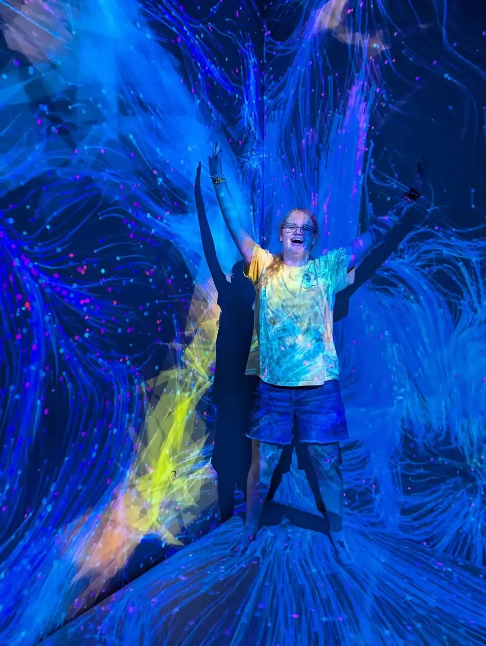 Real glow party — friends in neon outfits with hula hoops and balloon arch outdoors
