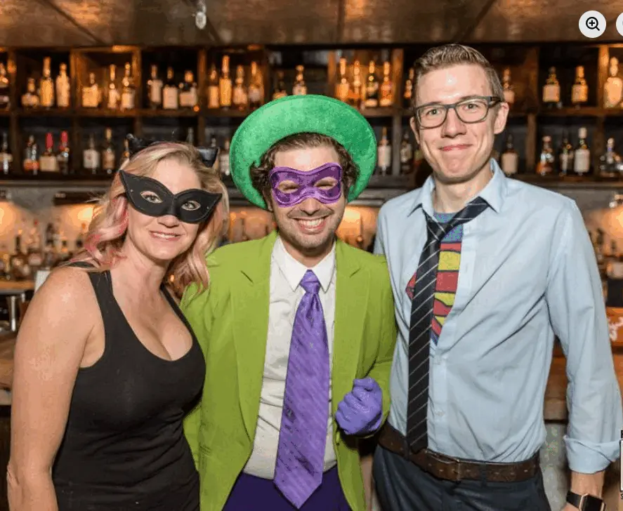 Real Heroes vs. Villains party — trio dressed as Catwoman, the Riddler, and Clark Kent