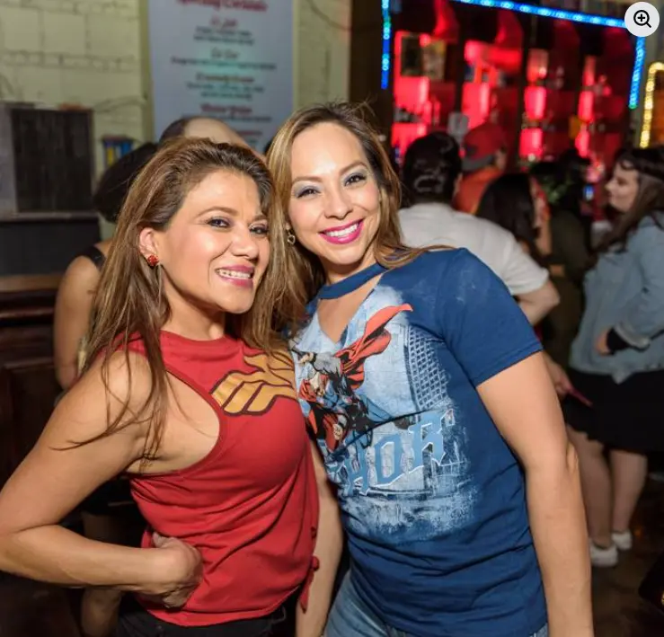 Real Heroes vs. Villains party — two women in Wonder Woman and Thor shirts at a bar