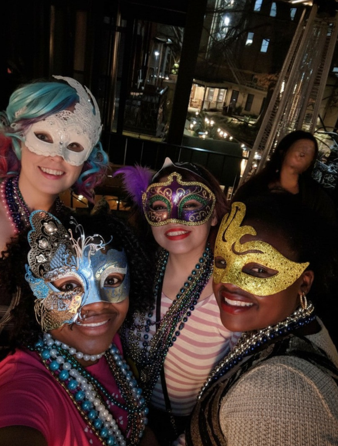 Real Mardi Gras party — four women in masquerade masks and beads taking a selfie outdoors at night