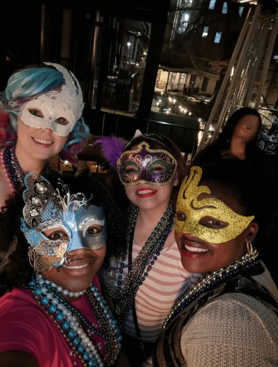 Real Mardi Gras party — four women in masquerade masks and beads taking a selfie outdoors at night