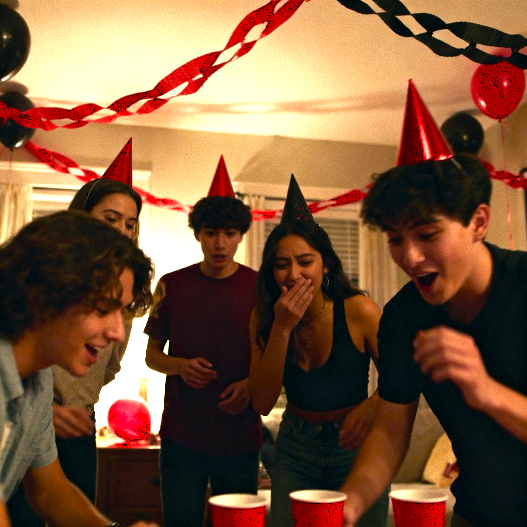 Minute to Win It party — friends laughing during a ping pong toss challenge indoors