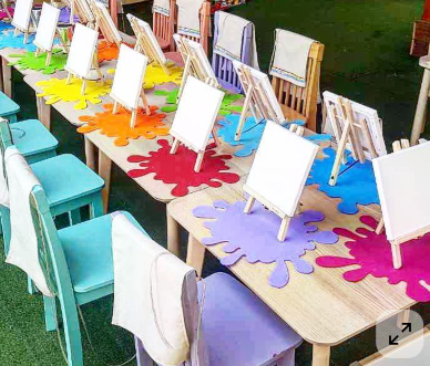 Paint & Sip inspiration — colorful outdoor painting station setup with canvases and paint splash mats