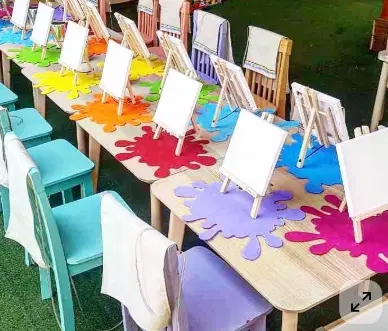 Paint & Sip inspiration — colorful outdoor painting station setup with canvases and paint splash mats