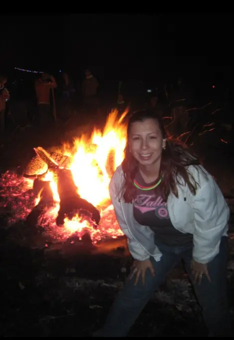 Woman smiling in front of a glowing bonfire at night