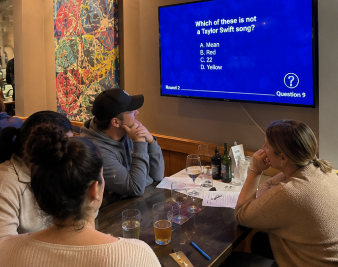 AI inspired trivia night — group focused on a Taylor Swift trivia question on a big screen