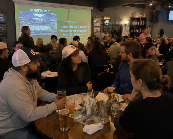 AI inspired trivia night — packed bar with teams discussing answers to a sports stadium question