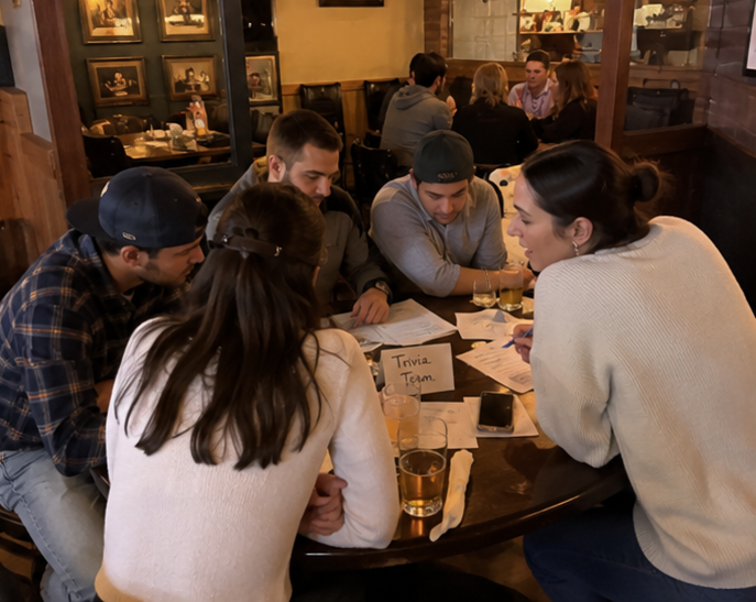 AI inspired trivia night — team huddled around answer sheets at a pub trivia night