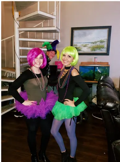 Real wig party — two women in purple and green tutus with colorful wigs