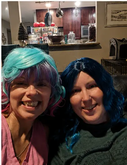 Real wig party — two women in blue and teal wigs laughing together